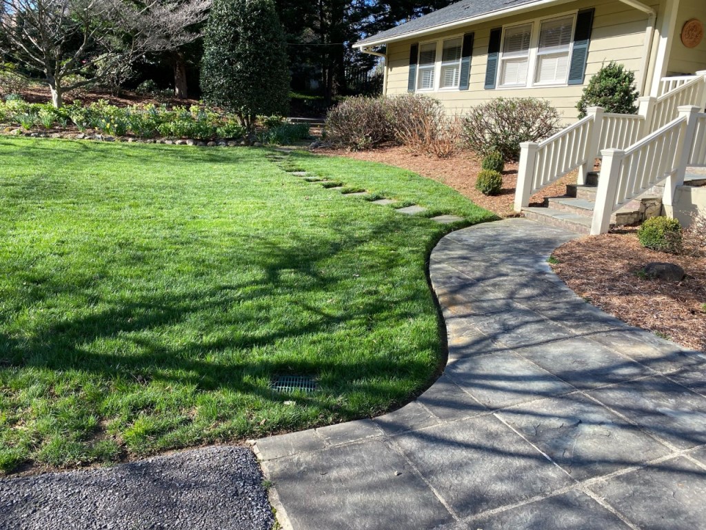 Lawn and landscape maintained beside a curved walkway